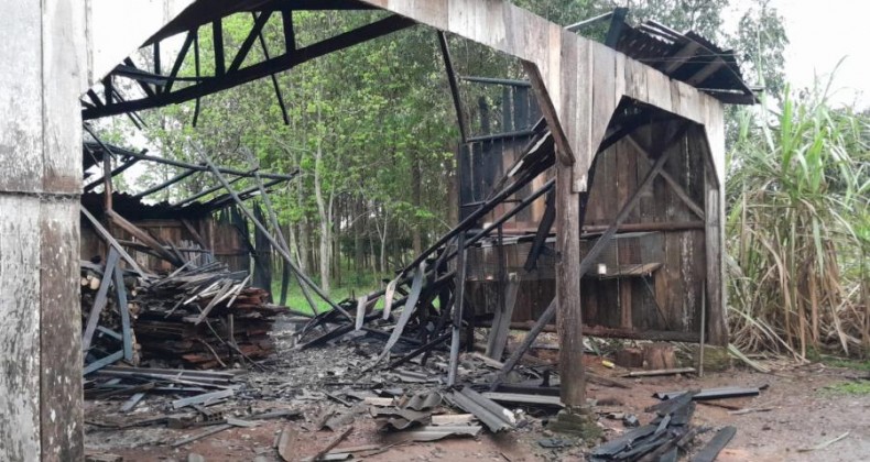 Moradores combatem incêndio em galpão com baldes de água.